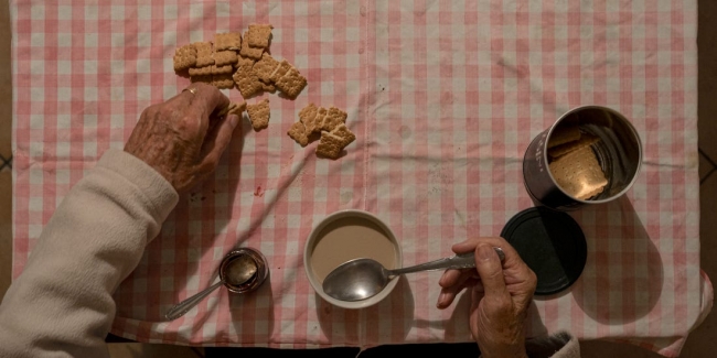 İtalya’daki evinde bisküvi yiyen bir yaşlı. Fotoğraf: Reuters
